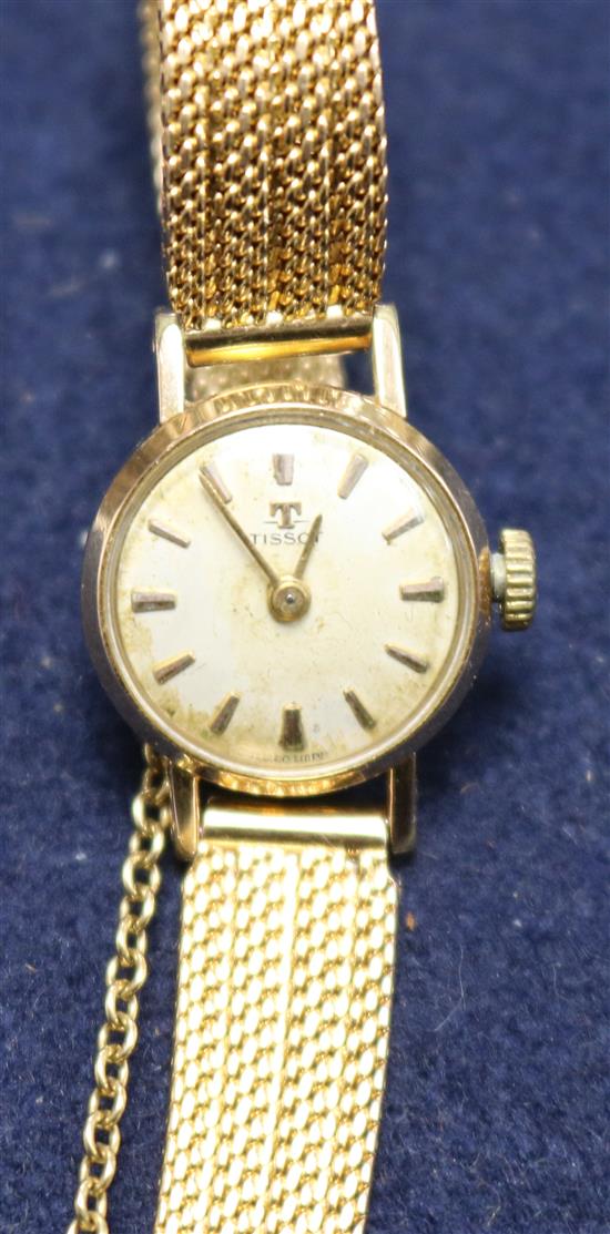 A ladys gold plated and steel Tissot manual wind wrist watch on a textured gold bracelet.
